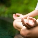 Mulher a meditar em jardim junto à agua